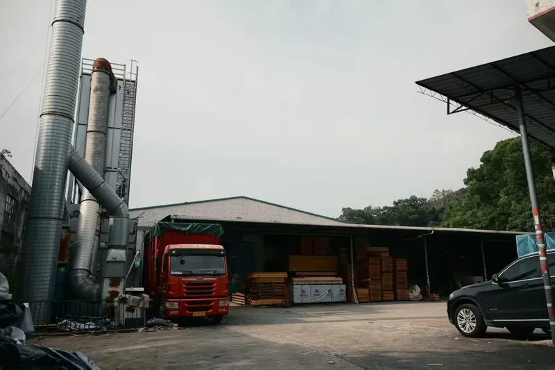 Truck loaded with timber and cabin components at the factory gate
