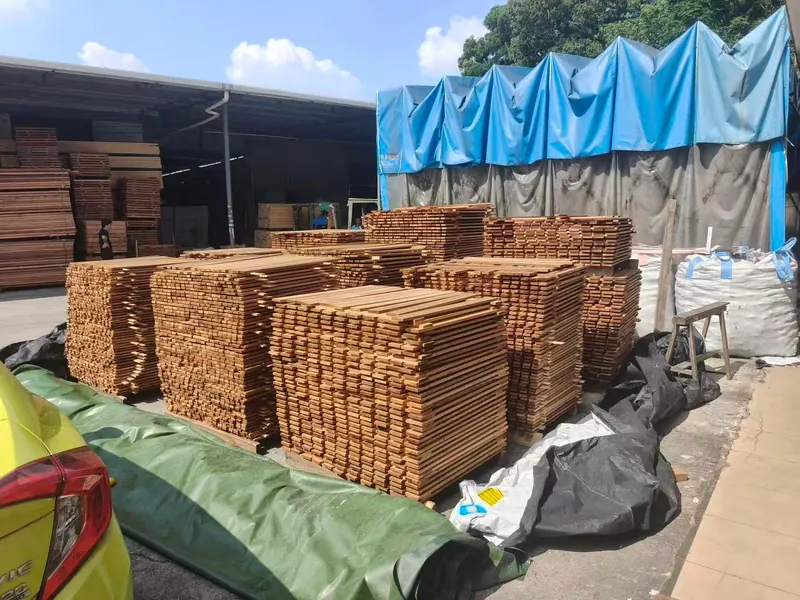 Bundles of timber board stacked outdoors and covered against the weather